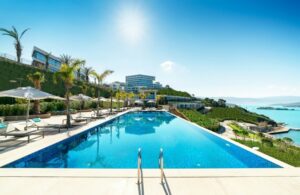 The hotel pool is surrounded by sun loungers, inviting guests to relax and enjoy the sunny atmosphere.